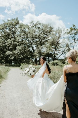 Bride walking with bridesmaid holding dress train